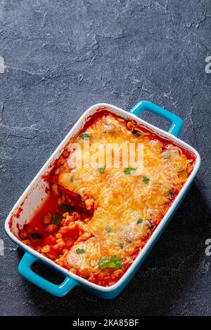 Vegetarische Enchilada Auflauf mit Tortillas, Sauce, Pinto-Bohnen, Mais, Zucchini und mexikanischen Käse in Backform auf Betontisch geschichtet, V Stockfoto