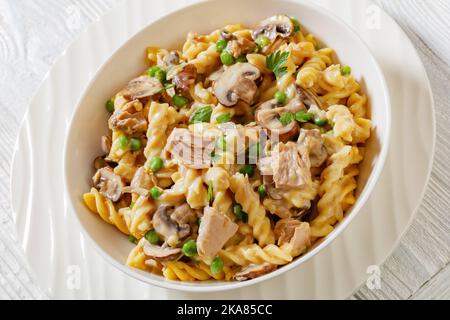 Nahaufnahme des Thunfisch-Pilz-Erbsenfusilli-Auflaufes mit cremiger Käsesauce in einer weißen Schüssel Stockfoto