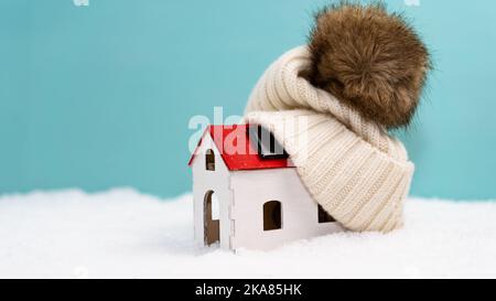 Haus im Schnee. Das Konzept der Zahlung für Heizung, steigende Heizkosten. Beanie auf Modellhaus. Vorbereitung auf den Winter. Stockfoto