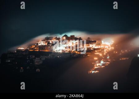 Ein atemberaubender Blick auf eine mystische Nebelwolke, die sich nachts über Imerovigli in Santorini, Griechenland, bildet Stockfoto