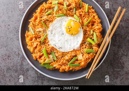 Hausgemachter Kimchi gebratener Reis mit gebratenem Ei aus der Nähe auf dem Teller auf dem Tisch. Horizontale Draufsicht von oben Stockfoto