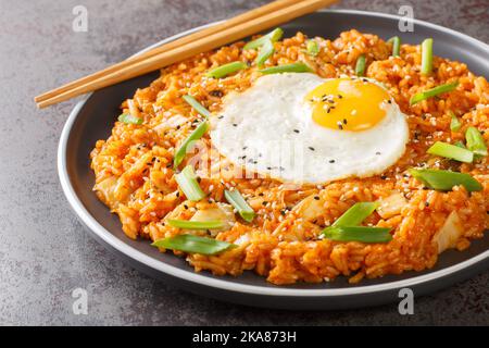 Hausgemachter Kimchi gebratener Reis mit gebratenem Ei aus der Nähe auf dem Teller auf dem Tisch. Horizontal Stockfoto