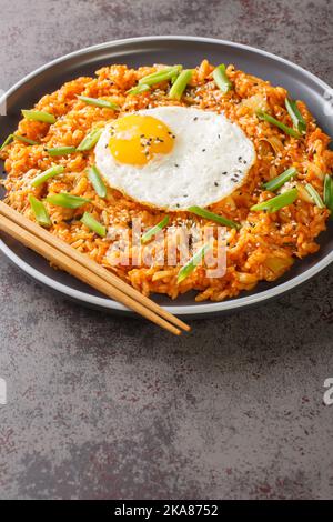 Kimchi gebratener Reis mit Ei Bokkeumap Konzept für koreanische Küche und Menü Nahaufnahme auf dem Teller auf dem Tisch. Vertikal Stockfoto