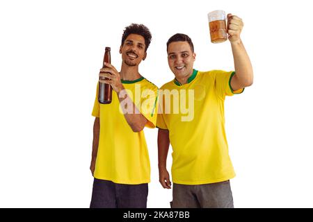 Black Brothers mit gelbem brasilianischem Hemd und Bierflaschenjubeln isoliert auf Weiß. Fußballfans jubeln über den Sieg Brasiliens. Stockfoto