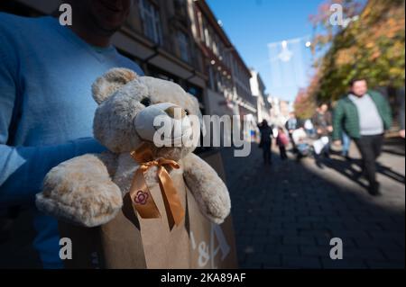 Wiesbaden, Deutschland. 01.. November 2022. Ein Mainzer hält in der Innenstadt eine Einkaufstasche mit einem Teddybär aus der Galerie in der Hand. Viele Rheinland-pfälzische Gäste nutzen den Urlaub am 1. November, um im benachbarten Hessen einkaufen zu gehen. Dort ist Allerheiligen ein normaler Arbeitstag. Quelle: Sebastian Gollnow/dpa/Alamy Live News Stockfoto