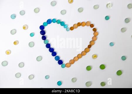 Bunte runde polierte Glassteine in Herzform mit Streuer-Glassteinen auf isoliertem Hintergrund. Hochwertige Fotos Stockfoto