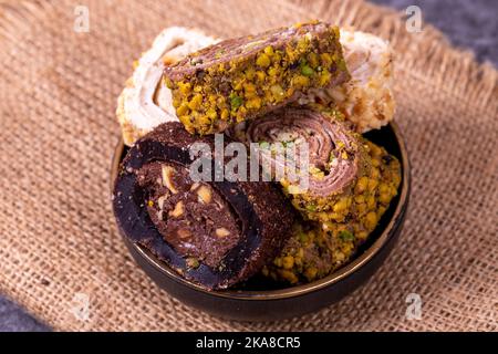 Gemischte türkische Delight-Sorten auf dunklem Hintergrund. Türkische Köstlichkeiten mit Pistazien, Haselnüssen und Früchten. Nahaufnahme Stockfoto