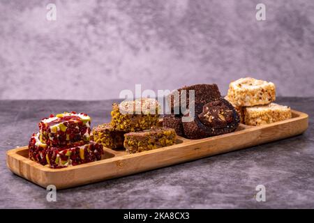 Gemischte türkische Delight-Sorten auf dunklem Hintergrund. Türkische Köstlichkeiten mit Pistazien, Haselnüssen und Früchten. Nahaufnahme Stockfoto