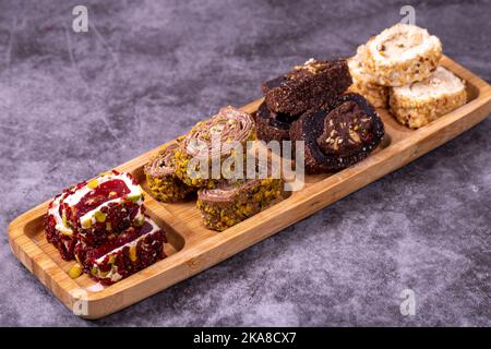 Gemischte türkische Delight-Sorten auf dunklem Hintergrund. Türkische Köstlichkeiten mit Pistazien, Haselnüssen und Früchten. Nahaufnahme Stockfoto