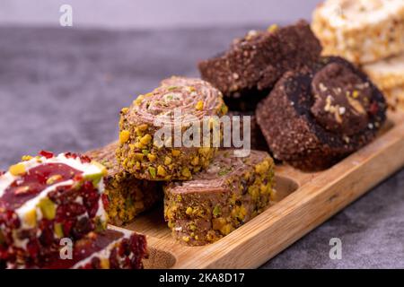 Gemischte türkische Delight-Sorten auf dunklem Hintergrund. Türkische Köstlichkeiten mit Pistazien, Haselnüssen und Früchten. Nahaufnahme Stockfoto