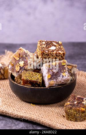 Gemischte türkische Delight-Sorten auf dunklem Hintergrund. Türkische Köstlichkeiten mit Pistazien, Haselnüssen und Früchten. Nahaufnahme Stockfoto