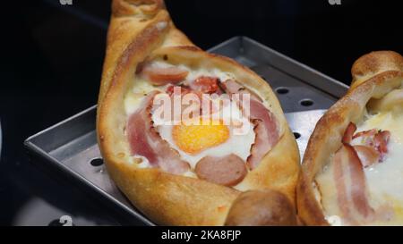 Eine Art Khachapuri-Essen mit Speck und Würstchen Stockfoto