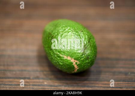 Eine Nahaufnahme einer reifen grünen Avocado auf einem Holztisch Stockfoto