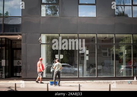 Bild von zwei jungen Männern, die als Fensterputzer im Stadtzentrum von Belgrad, Serbien, in einem Geschäftsgebäude Fenster putzen. Stockfoto