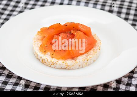 Leckeres Reiskuchen-Sandwich mit frischen Lachsscheiben auf weißem Teller. Einfache Frühstück und Diät-Essen. Knäckebrot mit rotem Fisch. Gesunder Ernährungs-Snack Stockfoto