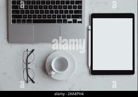 Geöffneter Laptop mit digitalem Tablet mit weißem leerem Bildschirm. Auf Marmortisch, Arbeitsplatz Stockfoto