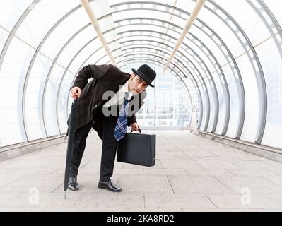 Die Stadt Gent, Geschäftsunsicherheit. Ein Londoner Geschäftsmann in einem traditionellen Melone Hut in einer vorsichtigen und verdächtigen Stimmung. Aus einer verwandten Bildserie. Stockfoto