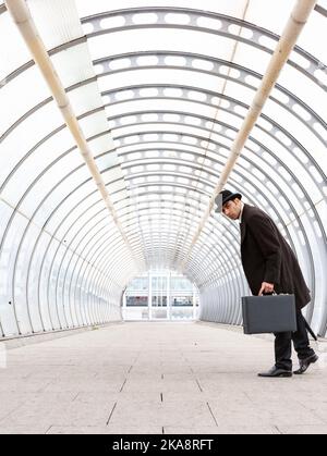 The City Gent, Business Photobomber. Ein traditioneller Londoner Geschäftsmann mit Melone dreht sich, um sich der Kamera zu stellen. Aus einer verwandten Bildserie. Stockfoto