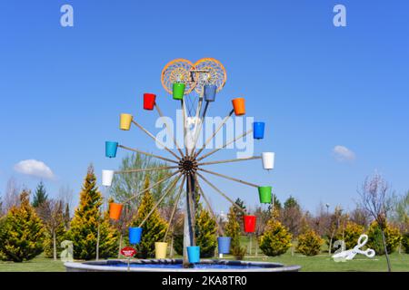 Wassermühle mit bunten Eimern im Park Stockfoto