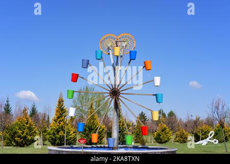 Wassermühle mit bunten Eimern, sonniger Tag im Park Stockfoto