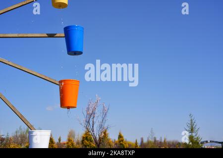 Wassermühle mit bunten Eimern, sonniger Tag im Park Stockfoto