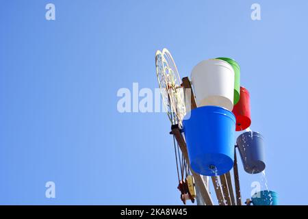 Wassermühle mit bunten Eimern, sonniger Tag im Park Stockfoto