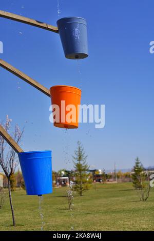 Wassermühle mit bunten Eimern, sonniger Tag im Park Stockfoto