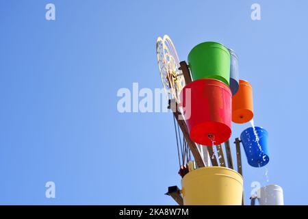 Wassermühle mit bunten Eimern, sonniger Tag im Park Stockfoto