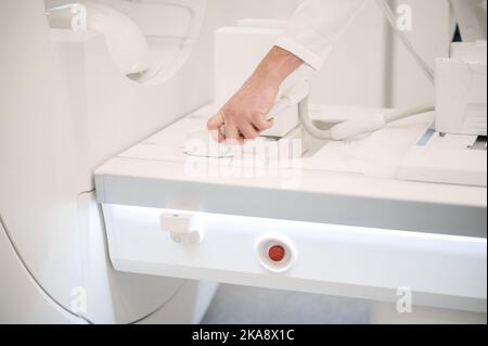 Nahaufnahme der Hände des Arztes, die einen MRT-Scanner vorbereiten Stockfoto