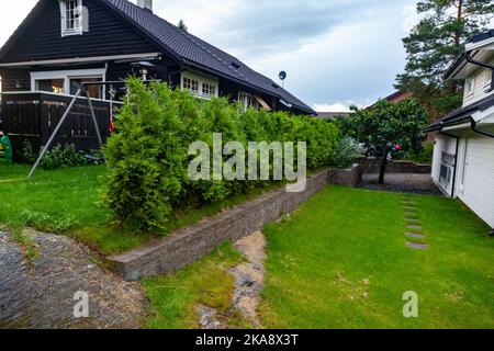Ein grüner Garten vor einem Haus mit dunkelgrauen Wänden und Dach Stockfoto