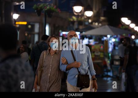 Bild einer weißen kaukasischen Frau und eines Mannes in belgrad, serbien, der in den Straßen von Belgrad, der Hauptstadt Serbiens, spazierend, während er eine Atemschutzmaske trägt Stockfoto