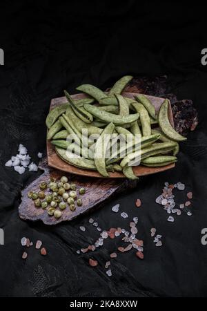 Gesund gerösteter Zucker schnappen Erbsen auf dunklem Holzhintergrund. Hausmannskost, Dunkler Ton, Platz für Text, selektiver Fokus. Stockfoto