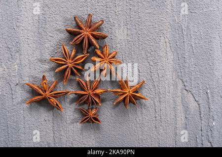 Weihnachtsbaum aus trockenen Anissternen auf grauem, rauem Hintergrund, Draufsicht. Weihnachtskarte. Das Konzept des neuen Jahres. Stockfoto