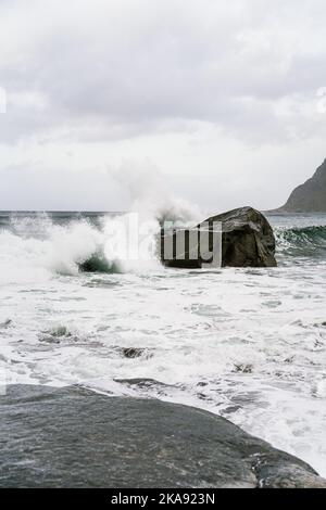 Wellen, die zu einem Felsbrocken am Strand von Utakleiv in Lofoten krachen Stockfoto