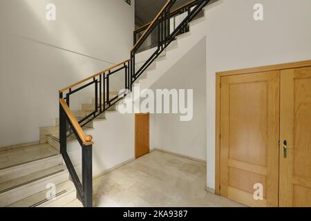 Treppen mit Marmorstufen und Handläufen aus Holz und schwarz lackiertem Metall Stockfoto