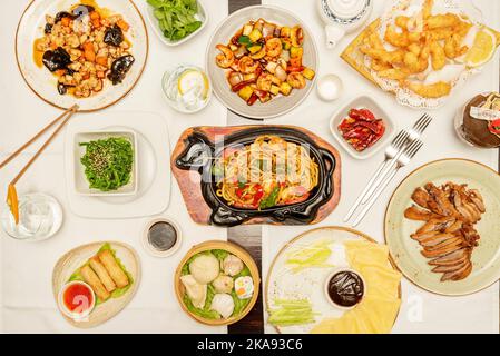 Set von hauptsächlich asiatischen und chinesischen Gerichten, udon-Nudeln mit Gemüse und Garnelen, vietnamesische Brötchen, Huhn mit Shiitake-Pilze, würzige Garnelen mit Stockfoto