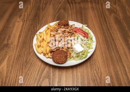 Kebab-Menüteller mit großem Stapel Hühnchen- und Lammfleisch mit Salat und pommes, Falafel, weißen Zwiebeln und frischem Käse Stockfoto