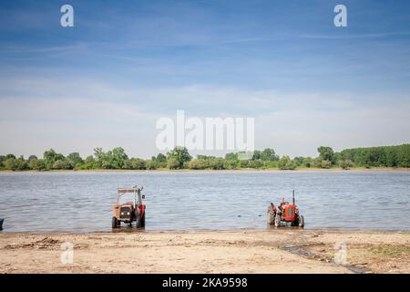 Panorama der Donau in Serbien mit Traktoren am Strand während eines sonnigen Sommernachmittages in Stari Slankamen, Serbien. Die Donau ist Europas sec Stockfoto