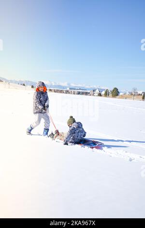 Kinder lachen haben Spaß Rodeln an einem sonnigen Tag im Winter denver Stockfoto