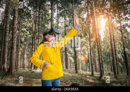 Frau mit Virtual-Reality-Headset, die in einem Wald steht Stockfoto