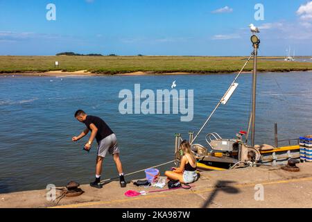 Paar Angeln auf Krebse am Kai von Wells Next The Sea ein beliebter Badeort an der nördlichen Norfolk-Küste im Osten Englands. Stockfoto