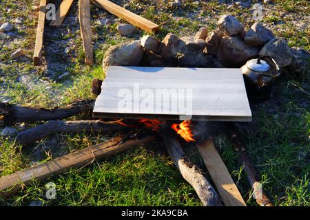 Marmor am Lagerfeuer zum Kochen und Teekannen am Feuer im Freien an einem sonnigen Sommertag Stockfoto