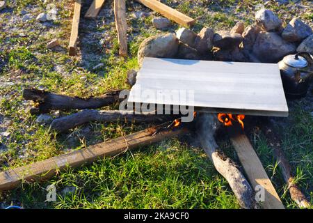 Marmor am Lagerfeuer zum Kochen und Teekannen am Feuer im Freien an einem sonnigen Sommertag Stockfoto