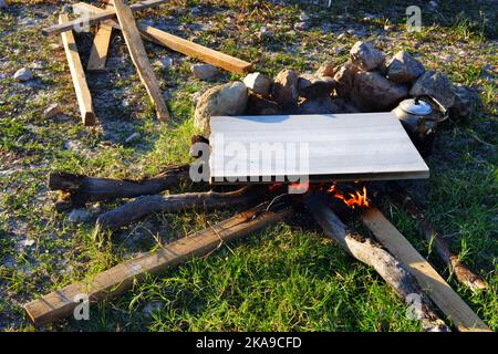 Marmor am Lagerfeuer zum Kochen und Teekannen am Feuer im Freien an einem sonnigen Sommertag Stockfoto