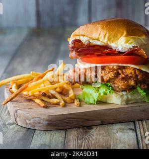 Eine Nahaufnahme eines hausgemachten, gebratenen Hähnchensandwiches, serviert mit frittierten Shoestring-Pommes. Stockfoto