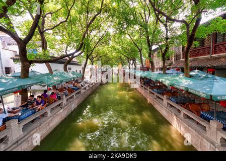 Tongli, China - 13. August 2011: Einer der vielen Kanäle in Tongli, auf denen Menschen an Restauranttischen sitzen. Tongli Es ist bekannt für ein System von Kanälen Stockfoto