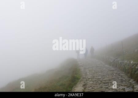 Drei Silhouetten von Menschen in den nebligen Tag auf felsigen Wanderweg in den Bergen Stockfoto
