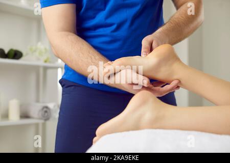 Professionelle Akupressur und Reflexzonenmassage, die spezielle Punkte beim Massieren der Füße der Frau drückt Stockfoto