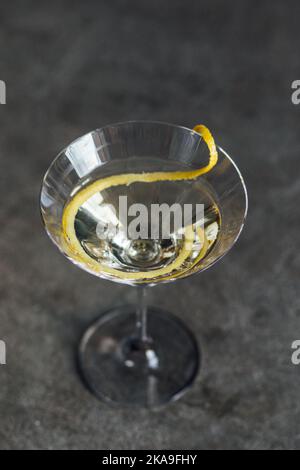 Blick auf Martini mit einer langen Zitronenverdrehung auf Betonboden Stockfoto