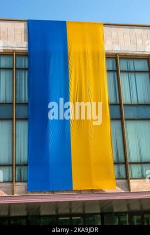 Die Nationalflagge der Ukraine flattert im Wind. Das nationale Symbol des ukrainischen Volkes auf dem Gebäude. Stockfoto